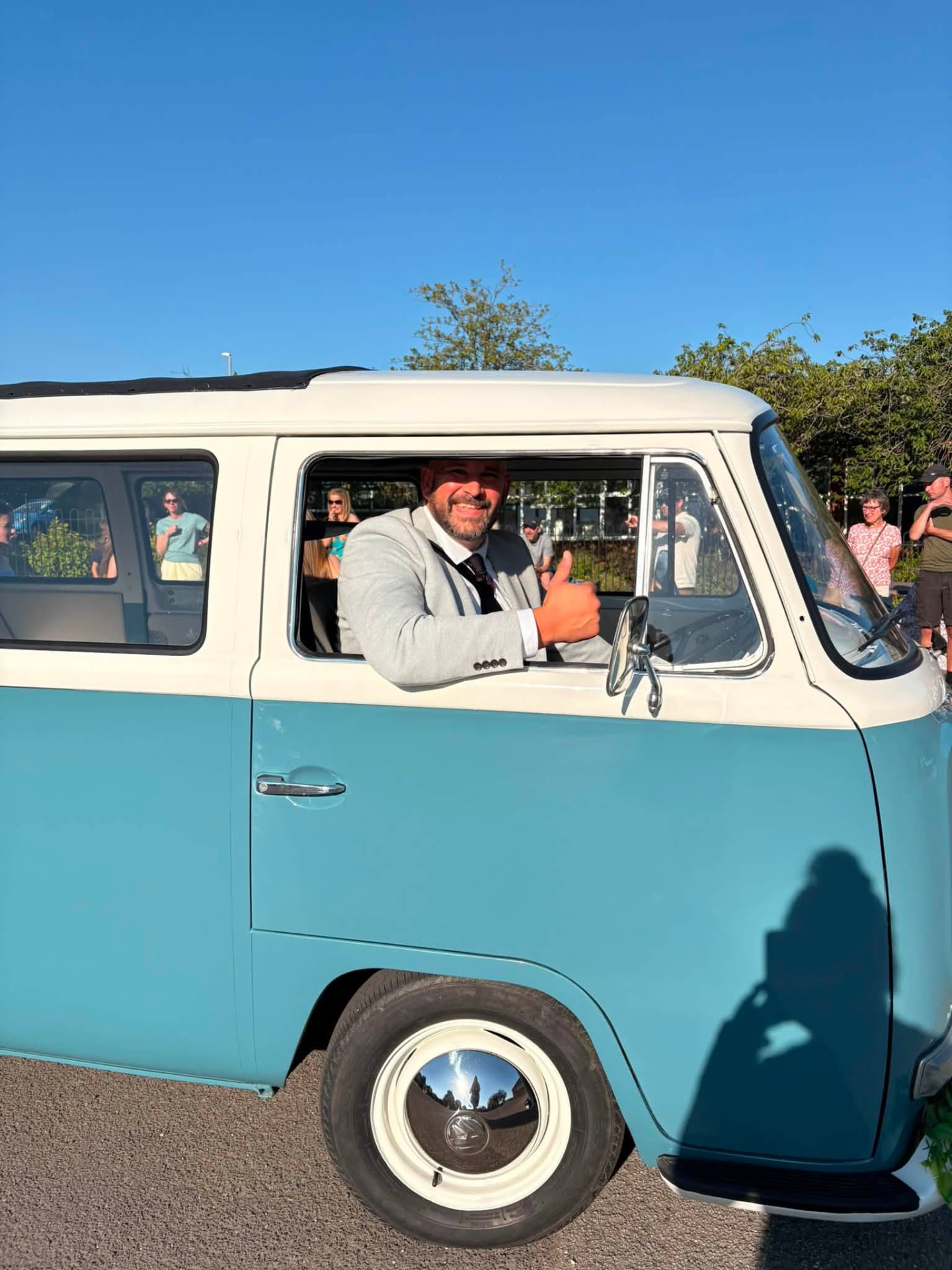 Rob Valinakis, owner and wedding car driver at Dream Day Bays, smiling from the window of the blue and cream VW camper in Lancashire